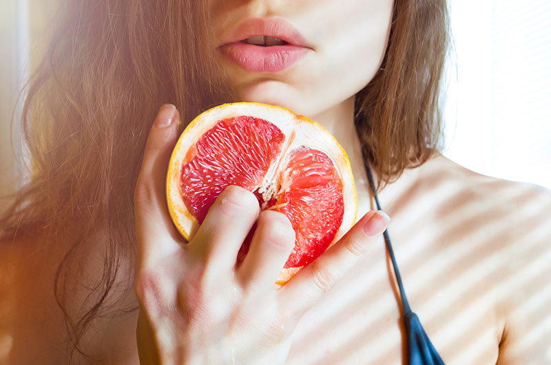 Frau imitiert Selbstbefriedigung an einer Grapefruit. 