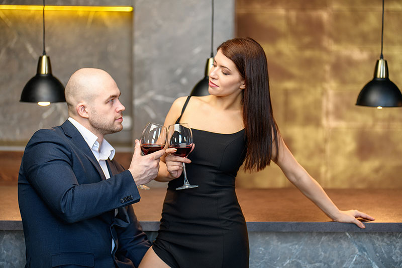Frau trinkt Wein mit einem Mann ohne Haare