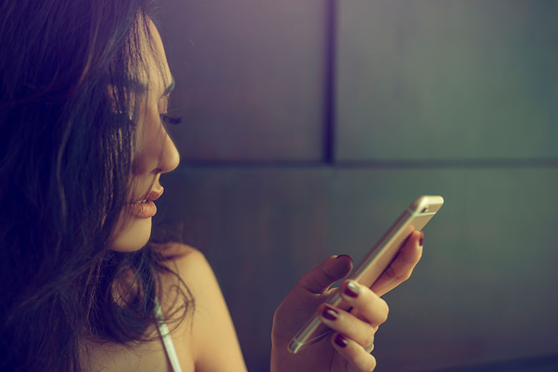 junge Frau benutzt Fremdgehen App auf dem Smartphone
