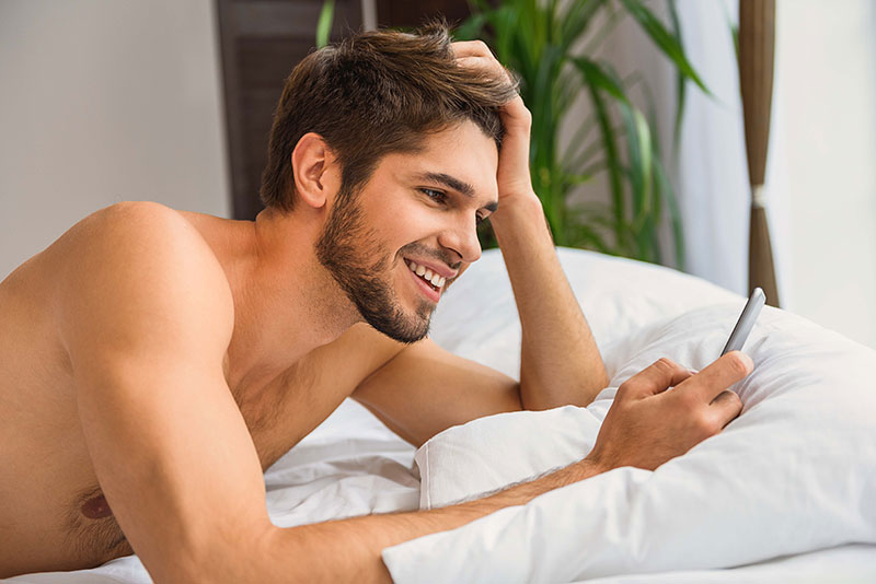 Mann freut sich über Nachricht in Sexdating App