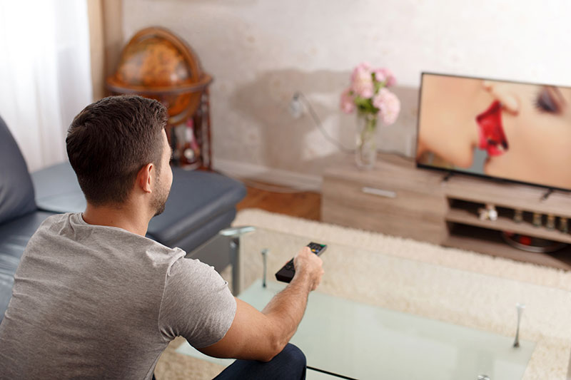 Mann schaut Porno Streams online auf dem TV