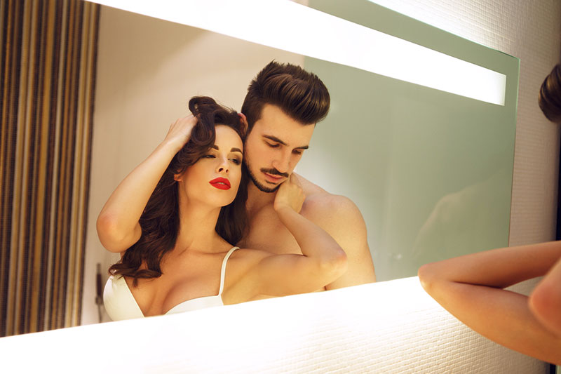Mann und Frau beobachten sich beim Sex im Spiegel